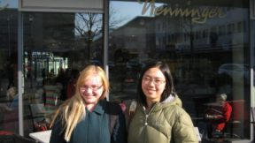 Zwei junge Frauen mit Brille stehen nebeneinander und lächeln.